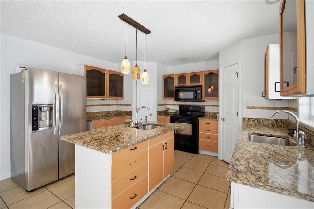 206 Taranto Way Kissimmee, FL 34758 - Photo 13 of 45 a kitchen with stainless steel appliances granite countertop a refrigerator stove and sink