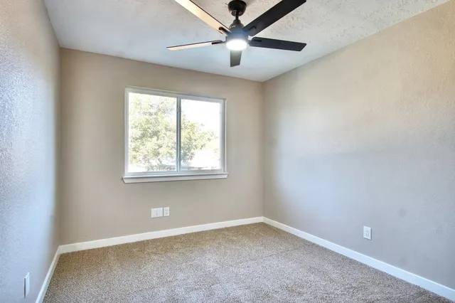 an empty room to ceiling fan and hallway