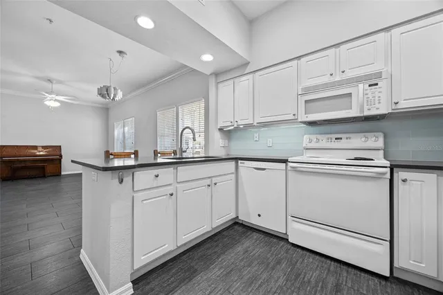 a kitchen with granite countertop white cabinets and white appliances
