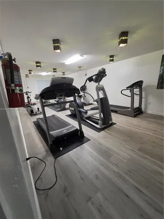 a room with gym equipment and wooden floor