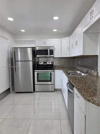 a kitchen with stainless steel appliances granite countertop a stove a refrigerator and a sink