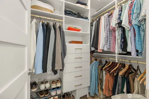 a view of walk in closet with clothes and shoes
