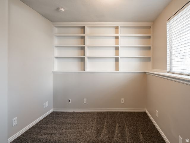 1446 West 1450 North Layton, UT 84041 - Photo 14 of 16 Built-in shelving unit with multiple compartments, neutral wall paint, white trim, window with blinds, and carpeted flooring