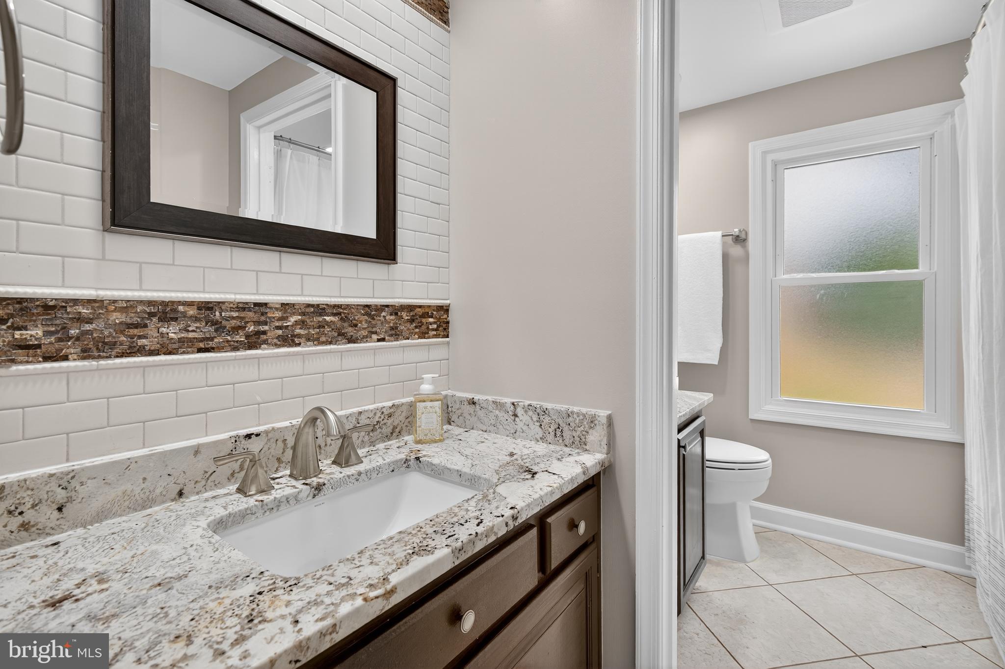 12100 Triple Crown Road North Potomac, MD 20878 - Photo 50 of 66 a bathroom with a granite countertop sink a toilet and a mirror