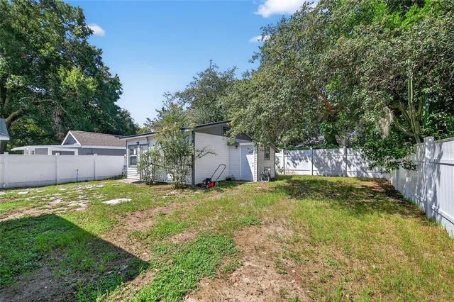 a backyard of a house with plants and large tree