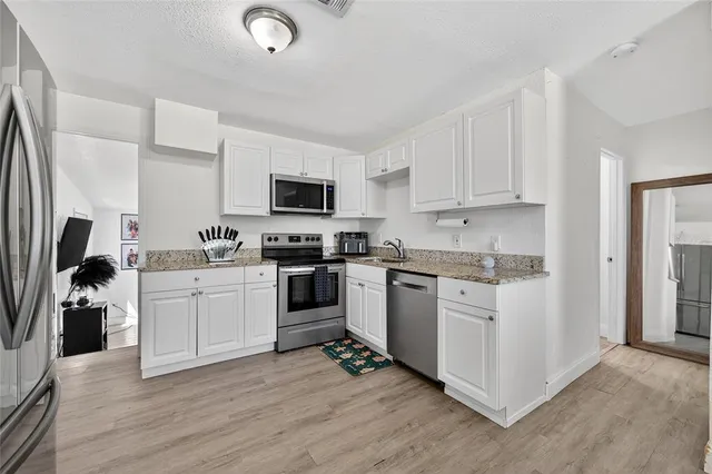 a kitchen with granite countertop a refrigerator stove and sink