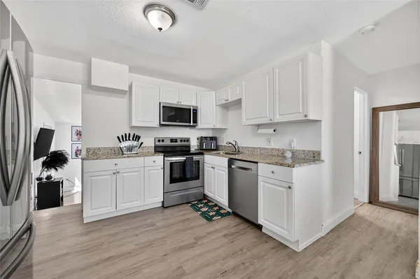 a kitchen with granite countertop a refrigerator stove and sink