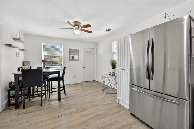 a kitchen with stainless steel appliances granite countertop a refrigerator a stove a dining table and chairs with wooden floor