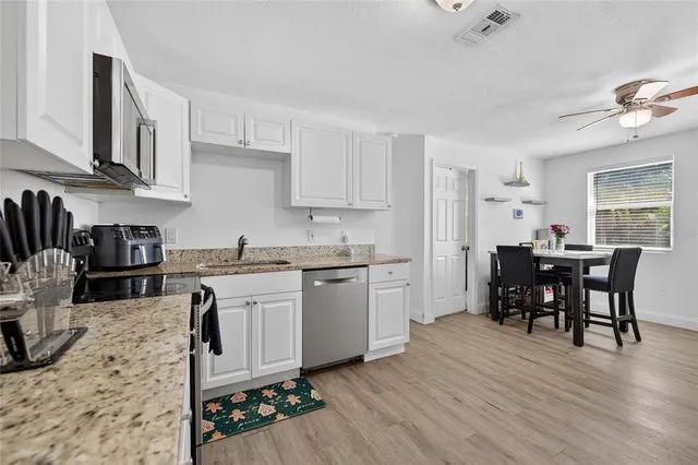 a kitchen with granite countertop cabinets stainless steel appliances dining table and chairs