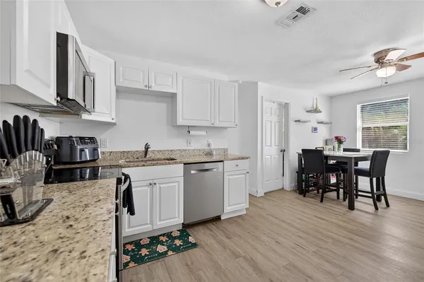 a kitchen with granite countertop cabinets stainless steel appliances dining table and chairs