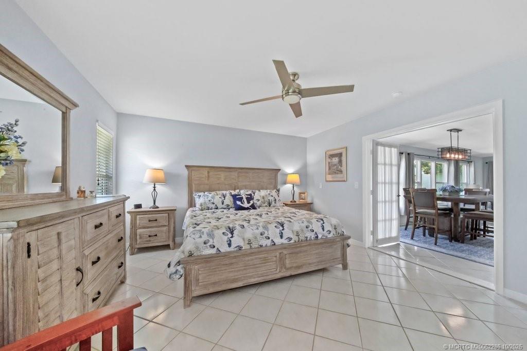 5157 Southeast Miles Grant Road Stuart, FL 34997 - Photo 11 of 32 a bedroom with a large bed and a chandelier