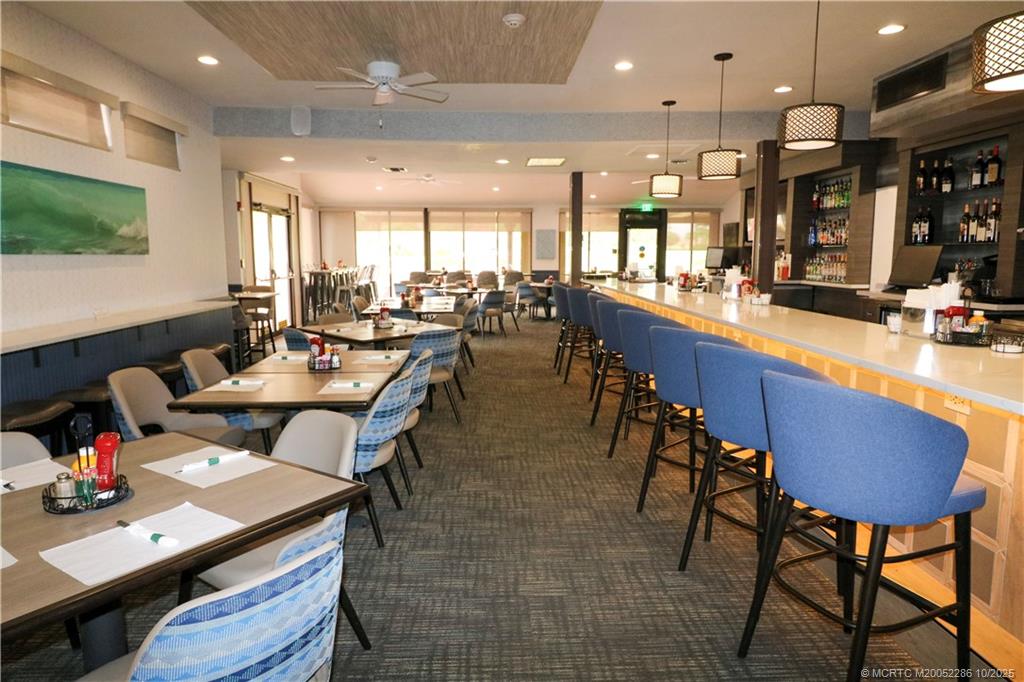 5157 Southeast Miles Grant Road Stuart, FL 34997 - Photo 27 of 32 a dining hall with stainless steel appliances kitchen island granite countertop a dining table and chairs
