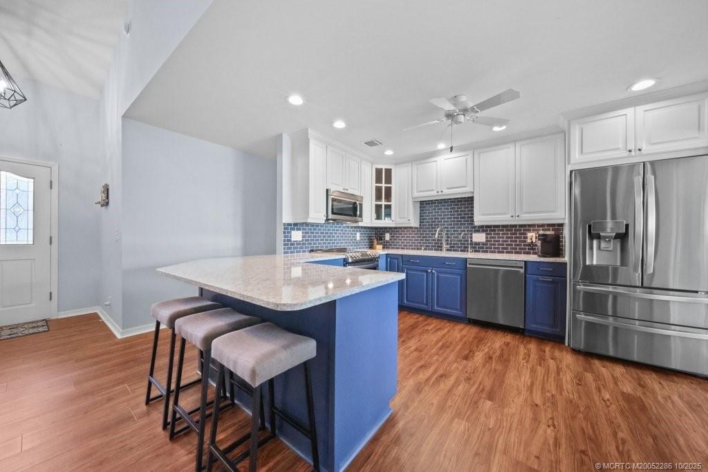 5157 Southeast Miles Grant Road Stuart, FL 34997 - Photo 4 of 32 a kitchen with stainless steel appliances granite countertop a table chairs sink refrigerator and microwave