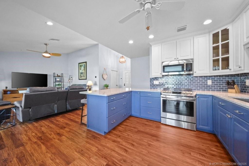 5157 Southeast Miles Grant Road Stuart, FL 34997 - Photo 5 of 32 a kitchen with stainless steel appliances kitchen island granite countertop a sink dishwasher a stove and a microwave oven with cabinets