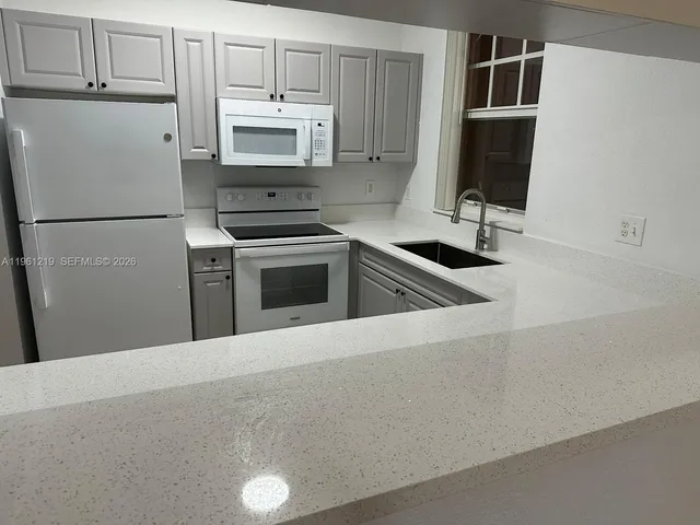a kitchen with granite countertop a refrigerator stove and microwave