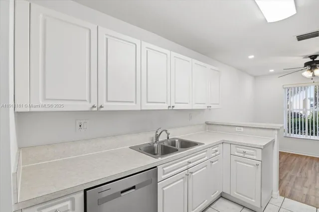 a kitchen with white cabinets and sink