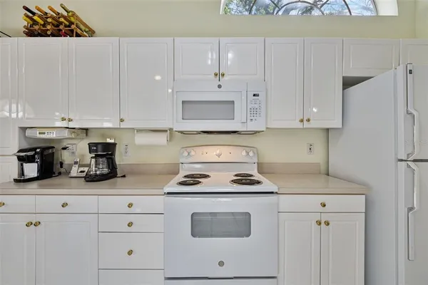 a kitchen with white cabinets and white appliances