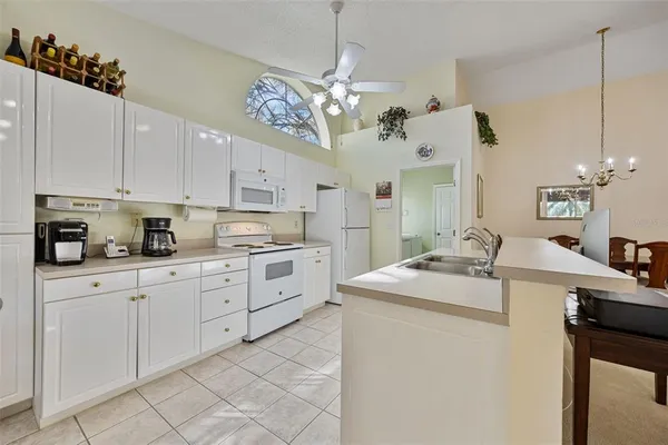 a kitchen with cabinets appliances and a chandelier