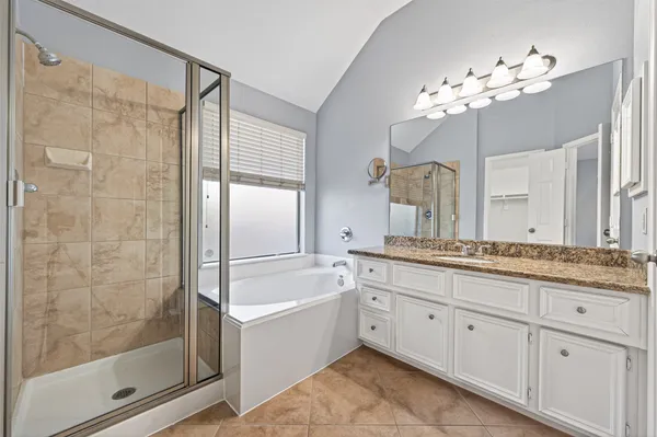 a bathroom with a granite countertop sink a mirror a shower and a bathtub