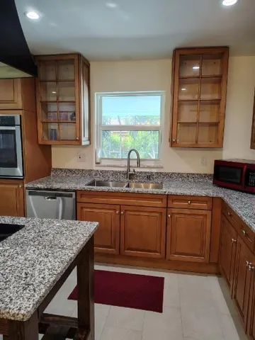 a kitchen with granite countertop kitchen island wooden cabinets a counter top space and stainless steel appliances