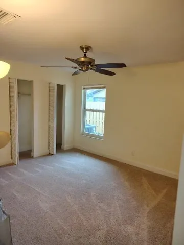 an empty room with windows and fan