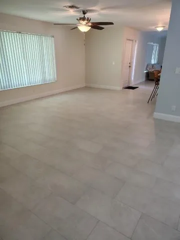 an empty room with a chandelier fan and windows