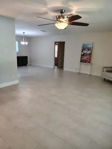 an empty room with windows and ceiling fan