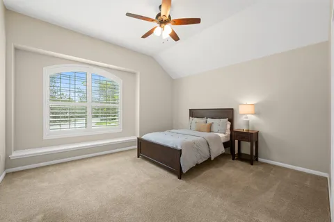 a spacious bedroom with a bed a chandelier and a window