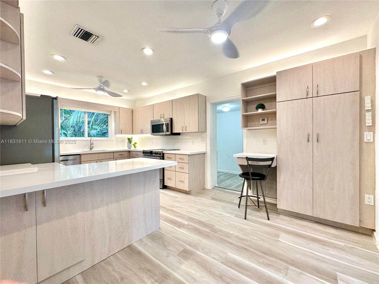 12501 Moss Ranch Road Pinecrest, FL 33156 - Photo 3 of 14 a kitchen with stainless steel appliances kitchen island granite countertop a table chairs sink and cabinets