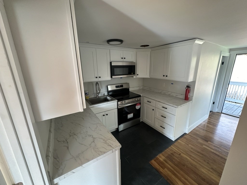 a kitchen with white cabinets and sink