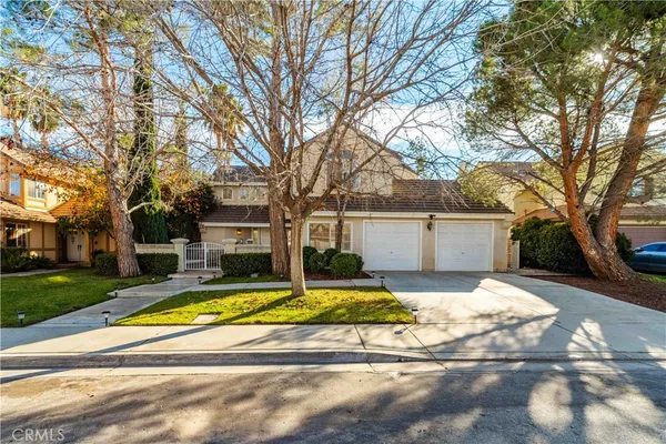 a view of a white house with a large tree and yard