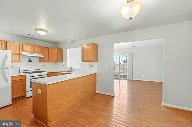 a large kitchen with stainless steel appliances granite countertop a stove a sink dishwasher and a refrigerator with wooden floor