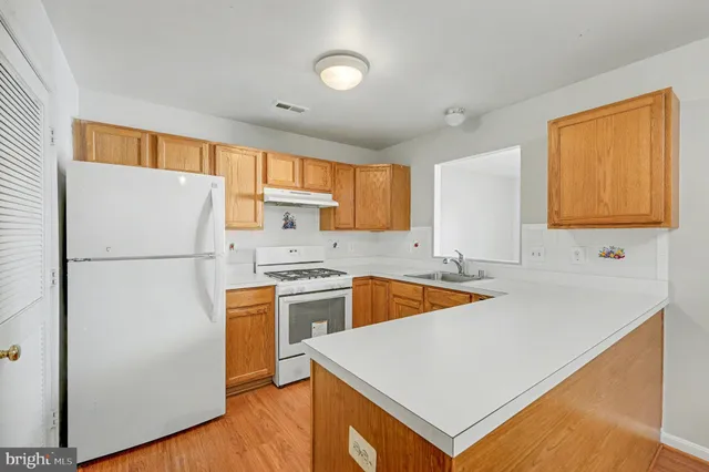 a kitchen with stainless steel appliances granite countertop a refrigerator a sink dishwasher a stove with white cabinets and wooden floor