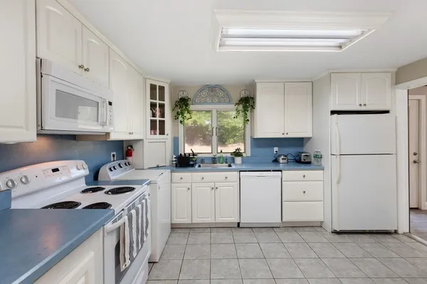 a kitchen with white cabinets and white appliances