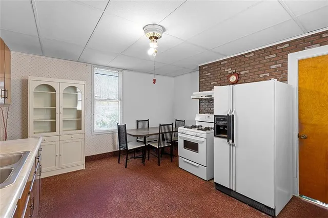 a kitchen with stainless steel appliances granite countertop a stove a refrigerator a sink a dining table and chairs with wooden floor