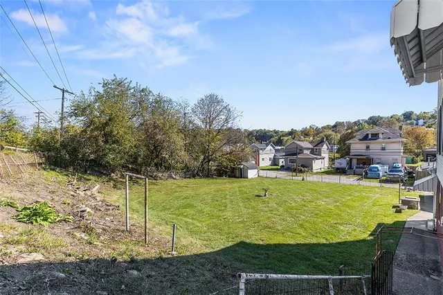 a view of a green field with houses in the back