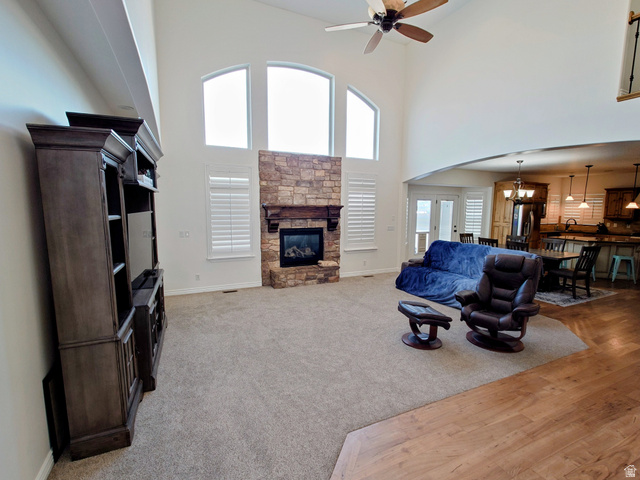 552 Sunset Crest Way Draper, UT 84020 - Photo 11 of 68 Living room featuring a high ceiling, a stone fireplace, ceiling fan, a chandelier, and light colored carpet