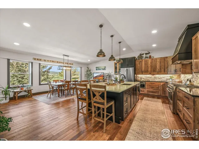 a kitchen with stainless steel appliances granite countertop a sink a stove and a wooden floors