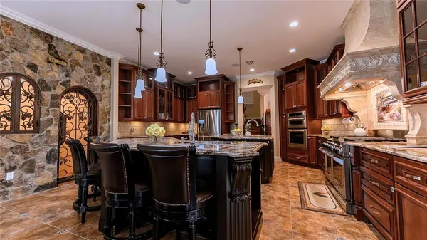 a kitchen with stainless steel appliances granite countertop a stove a sink dishwasher a dining table and chairs with wooden floor