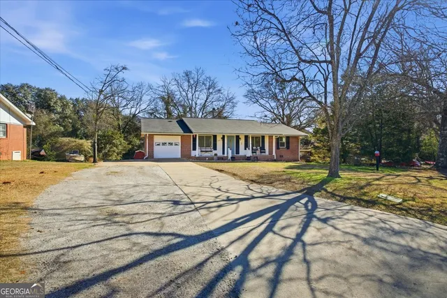 a view of house with yard and trees in the background