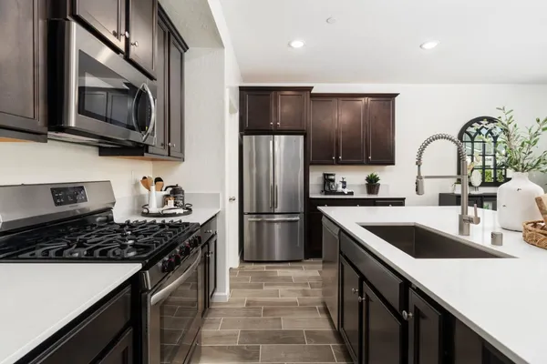 a kitchen with stainless steel appliances kitchen island granite countertop a stove a sink and a refrigerator