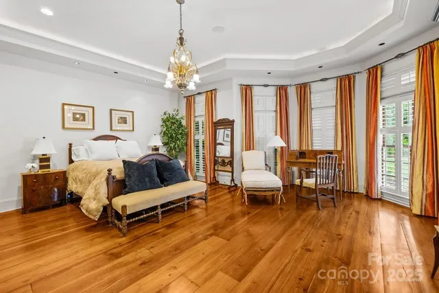 a spacious bedroom with a bed a chandelier and a large window
