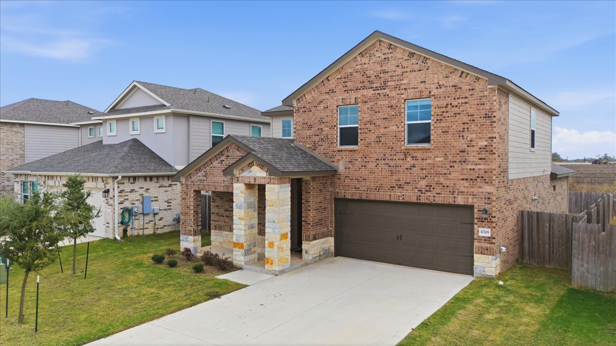 17705 Prairie Land Way Manor, TX 78653 - Photo 3 of 29 View of front facade featuring brick siding, driveway, and an attached garage