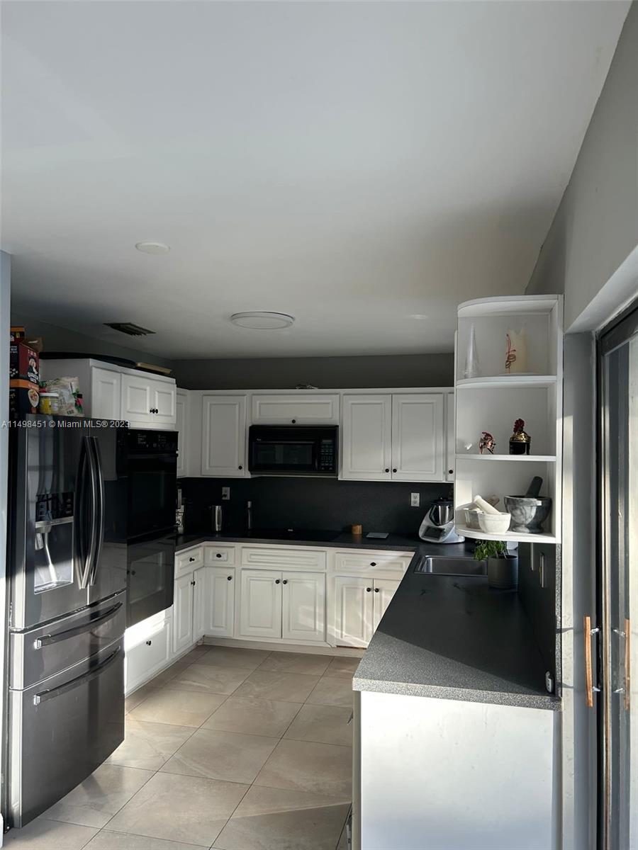 92 Juniper Road, Unit 92 Hollywood, FL 33021 - Photo 16 of 32 a kitchen with granite countertop a sink and white cabinets