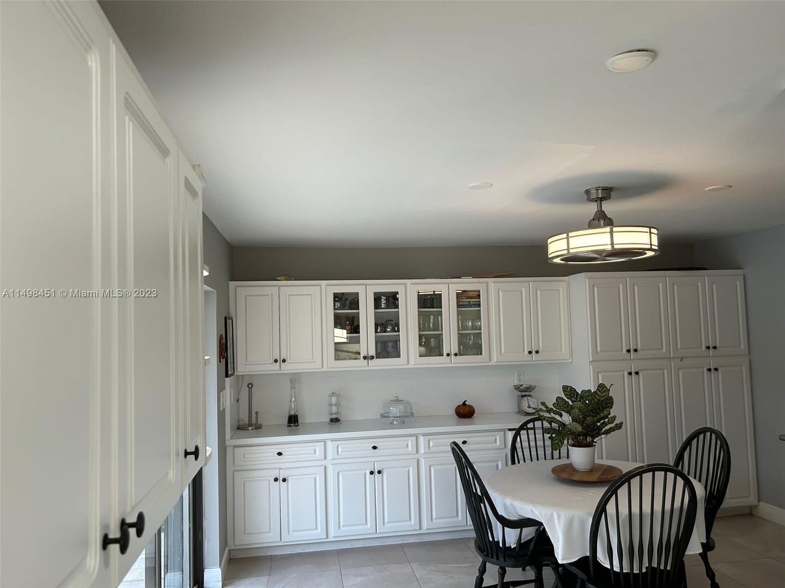 92 Juniper Road, Unit 92 Hollywood, FL 33021 - Photo 6 of 32 a kitchen with granite countertop a dining table chairs and white cabinets