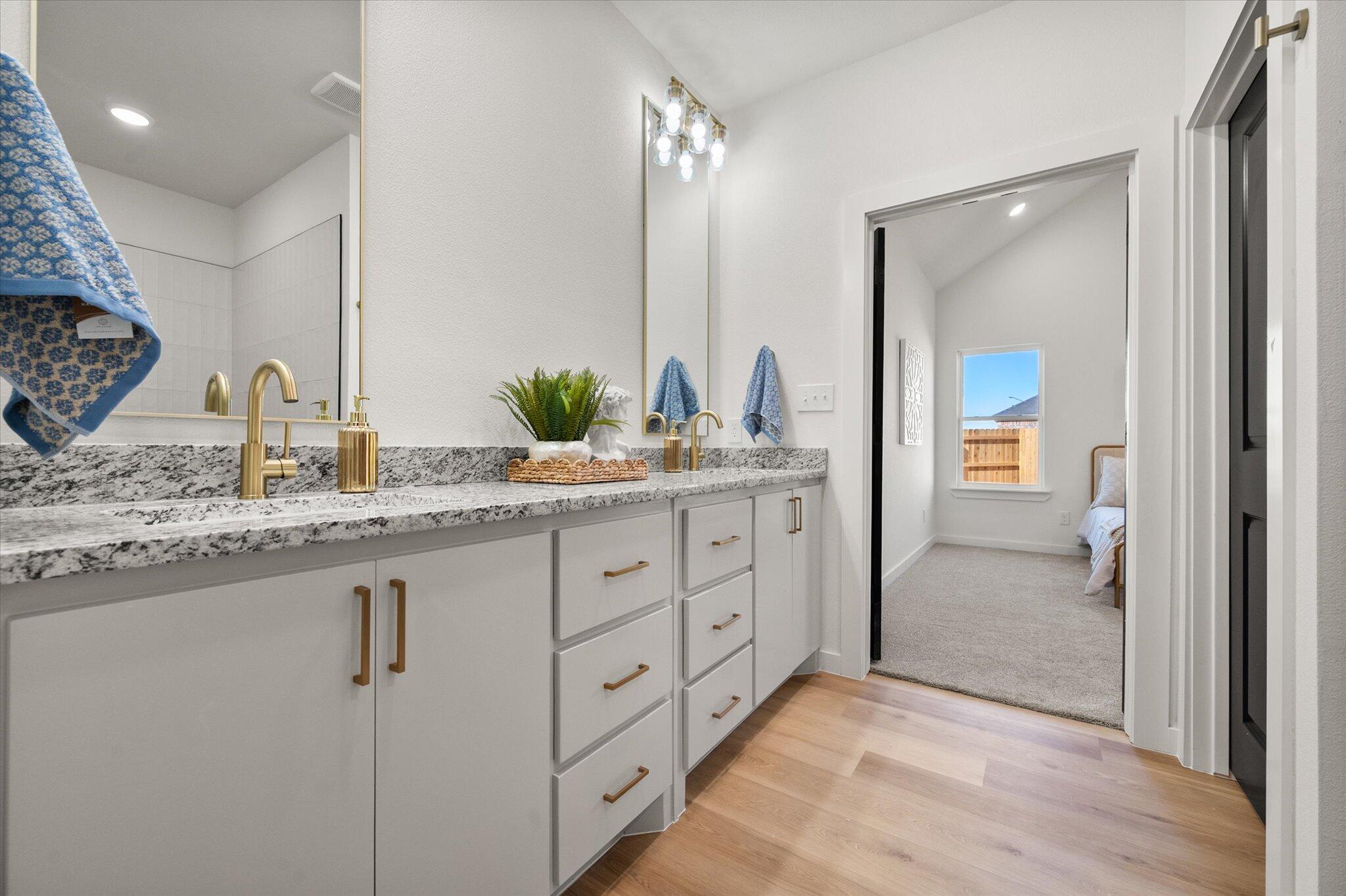 6928 14th Street Lubbock, TX 79416 - Photo 22 of 33 a bathroom with a granite countertop sink mirror and vanity