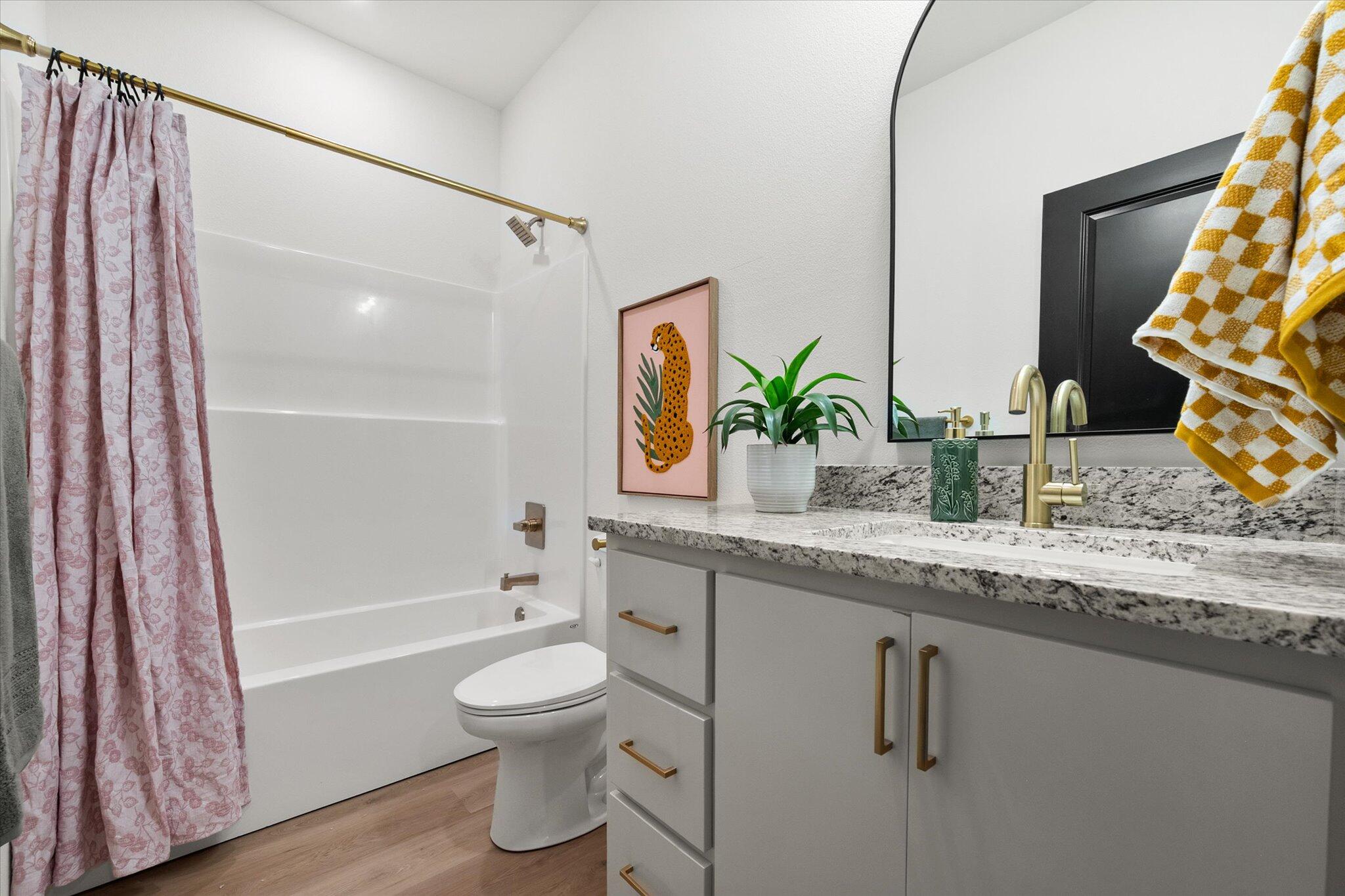 6928 14th Street Lubbock, TX 79416 - Photo 28 of 33 a bathroom with a granite countertop sink toilet a mirror and shower