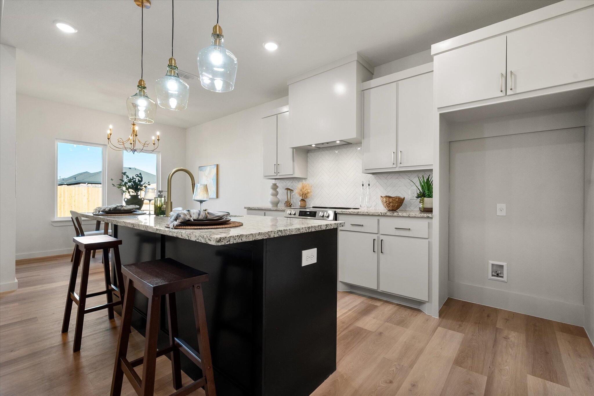 6928 14th Street Lubbock, TX 79416 - Photo 10 of 33 a kitchen with kitchen island granite countertop a sink cabinets and wooden floor