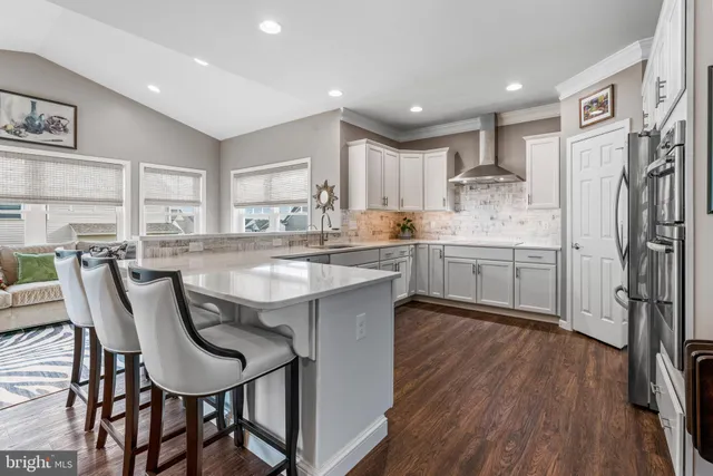 a kitchen with stainless steel appliances granite countertop a table chairs refrigerator and sink