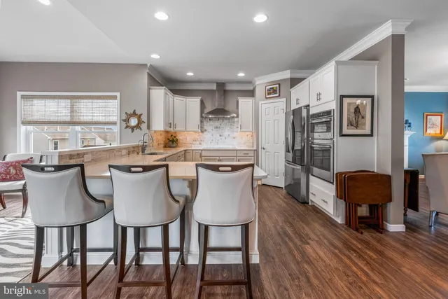 a dining room with stainless steel appliances kitchen island granite countertop a dining table chairs and a refrigerator